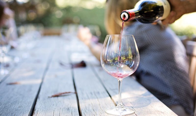 Une personne verse du vin rouge dans un verre afin de faire une dégustation.