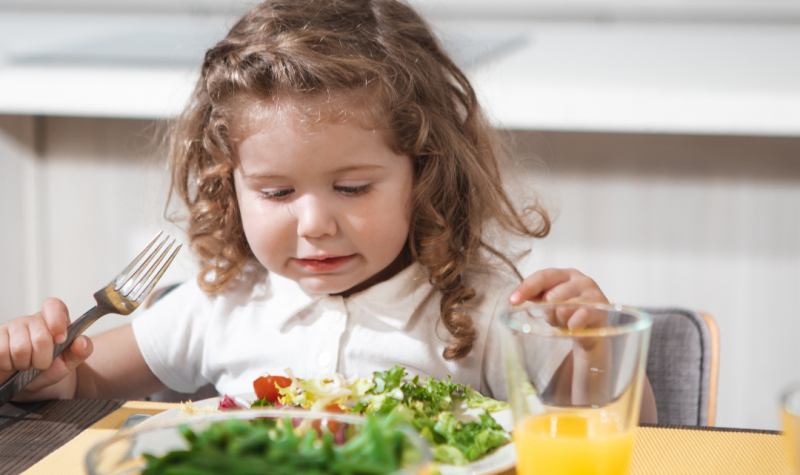 Una niña comiendo ensalada